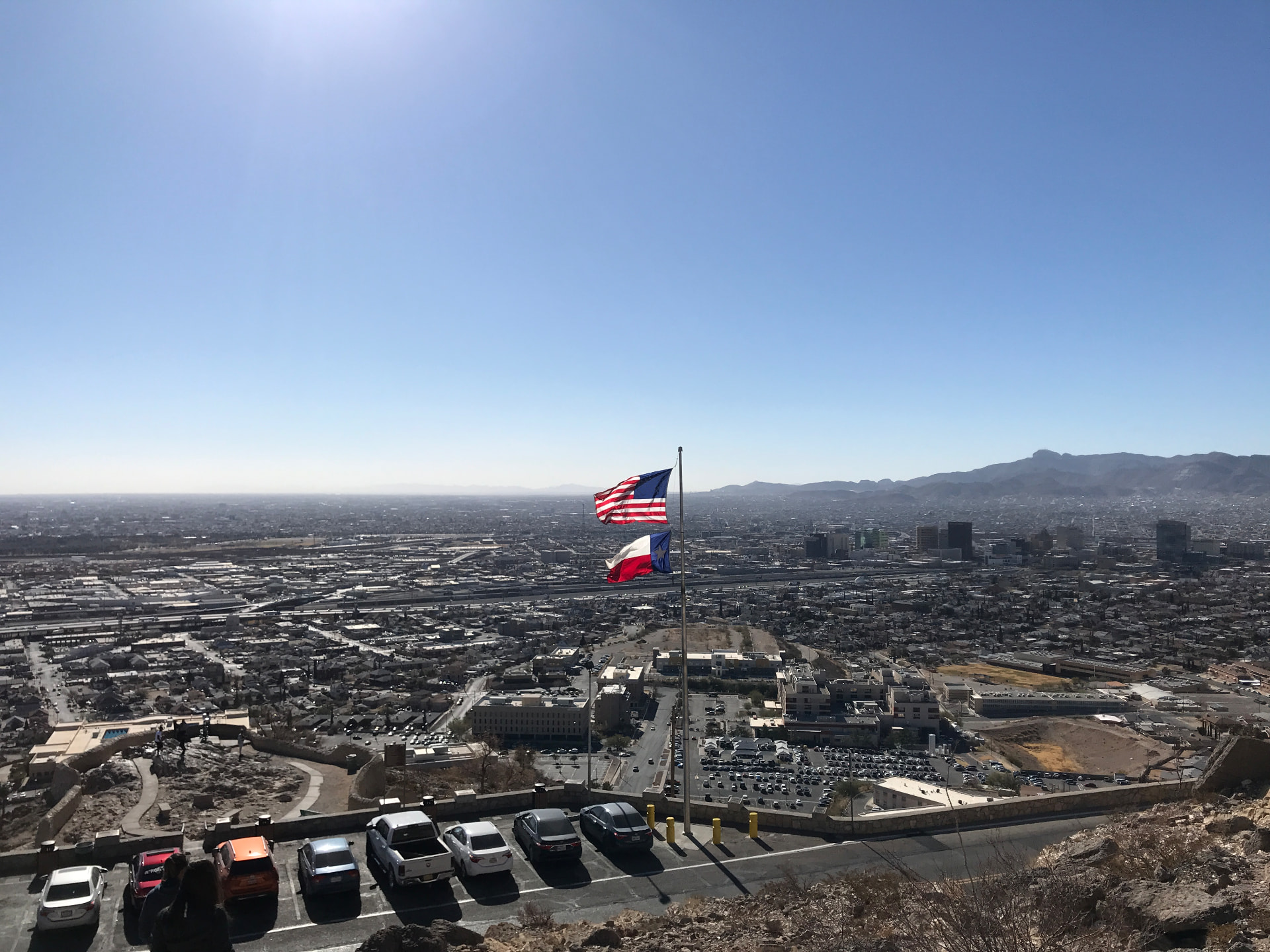 United States and Texas flags flying above an overlook of El Paso